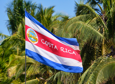 Costa Rican flag over backdrop of palm trees